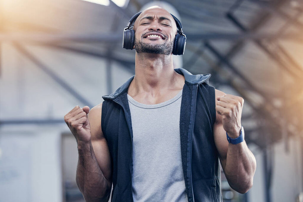 Hes totally in the mood for another amazing workout. Shot of a muscular young man cheering while listening to music in a gym. - Photo, Image