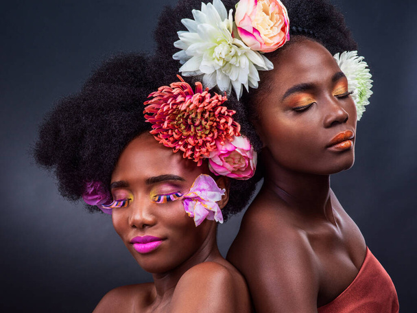 Квіти - найкращий друг дівчат. Обрізаний знімок двох красивих жінок позує разом з квітами у волоссі
. - Фото, зображення