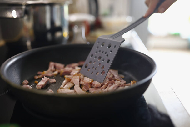 Chef revuelva jamón o rodajas de tocino en la sartén caliente, persona freír carne para el desayuno o la cena - Foto, Imagen
