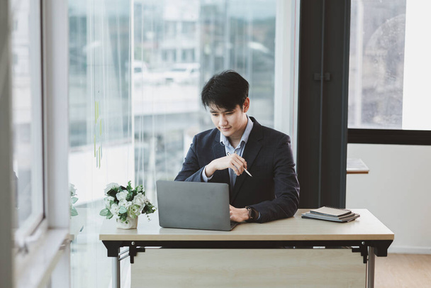 Asijský muž pracující ve své firmě, asijský podnikatel kontrolující notebook v soukromé kanceláři, výkonné místnosti, mladí manažeři začínající společnosti. Koncept správy spouštěcí společnosti. - Fotografie, Obrázek