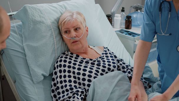 Mujer jubilada con tubo de oxígeno nasal hablando con el médico - Foto, Imagen