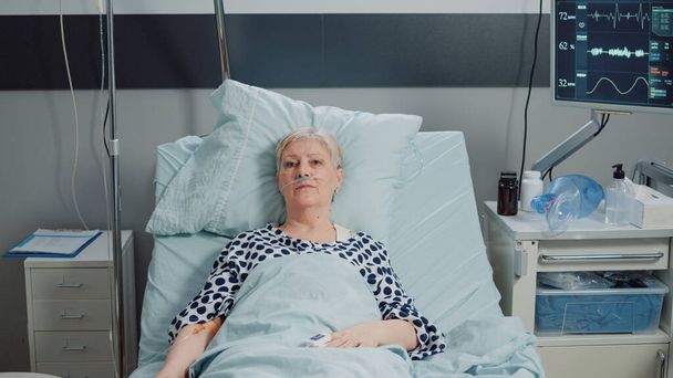 Elder patient with IV drip bag and nasal oxygen tube - Valokuva, kuva