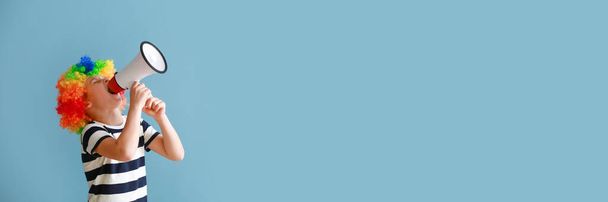 Roztomilý chlapeček v paruce klauna a s megafonem na barevném pozadí s prostorem pro text. Dubnová oslava Dne bláznů - Fotografie, Obrázek