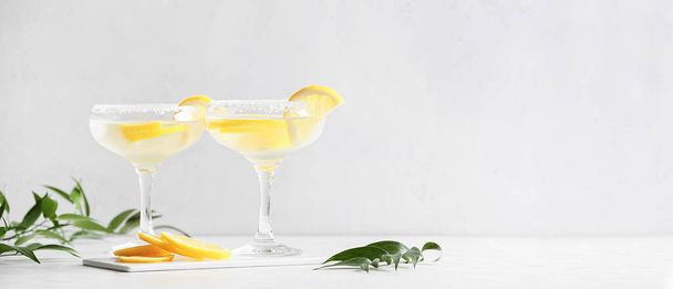 Glasses of tasty martini cocktail with lemon on light background with space for text - Photo, image