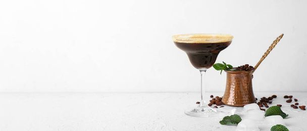 Ποτήρι νόστιμο espresso martini κοκτέιλ και jezve σε ελαφρύ φόντο με χώρο για κείμενο - Φωτογραφία, εικόνα