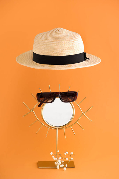 Composition with straw hat, mirror and glasses on color background - Photo, Image