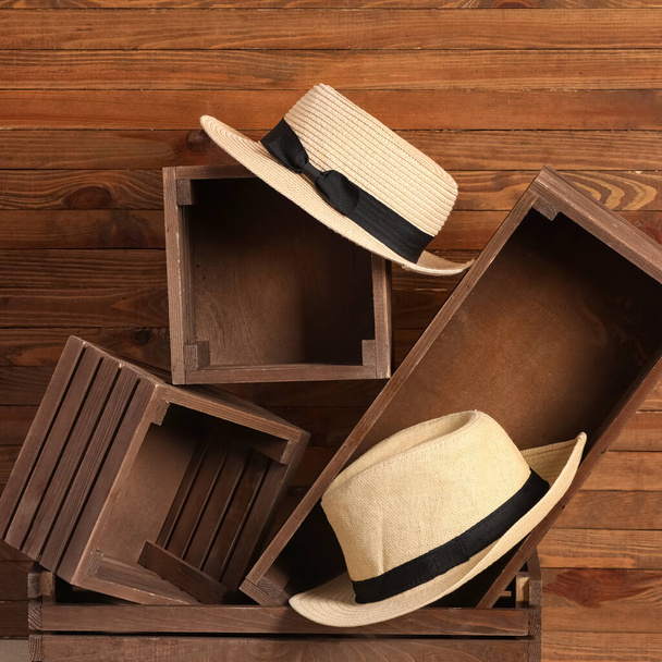 Солом'яні капелюхи та коробки на дерев'яному фоні
 - Фото, зображення