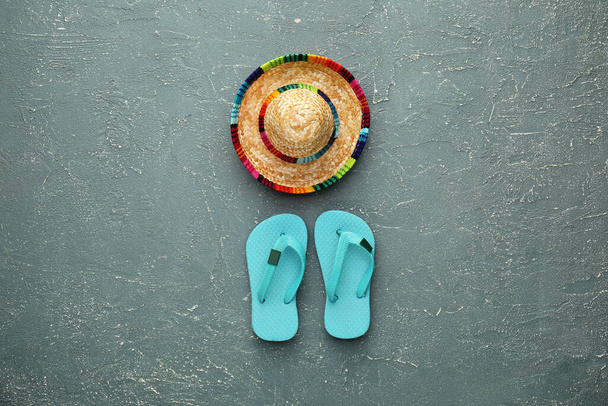 Straw sombrero and flip flops on color background - Foto, Imagen