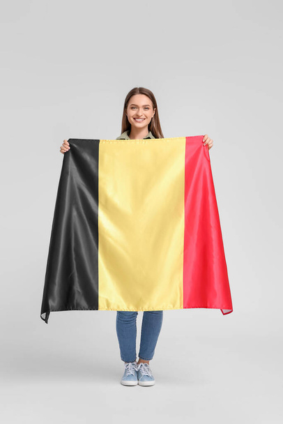 Jonge vrouw met vlag van België op lichte achtergrond - Foto, afbeelding