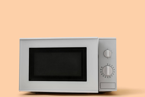 White microwave oven with opened door on beige background - 写真・画像