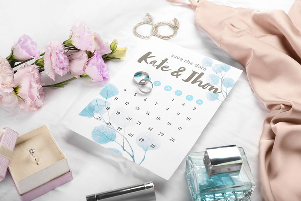 Wedding calendar, rings and bridal accessories on light fabric background - Fotó, kép