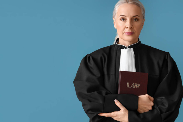 Érett női bíró köntösben törvény könyv kék háttér - Fotó, kép