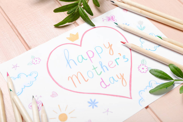 Card with text HAPPY MOTHER'S DAY, pencils and plant branches on pink wooden background, closeup - Foto, afbeelding