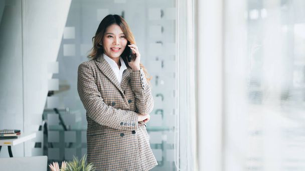 Asian woman talking on the phone, she is a salesperson in a startup company, she is calling customers to sell products and promotions. Concept of selling products through telephone channels. - Foto, Imagem