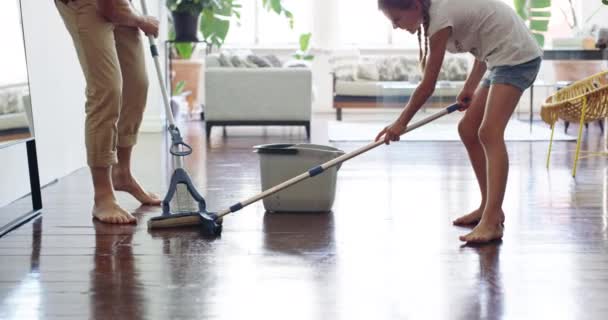 Teamwork makes the chores work. 4k video footage of a little girl mopping the floor with her father at home. - Filmati, video