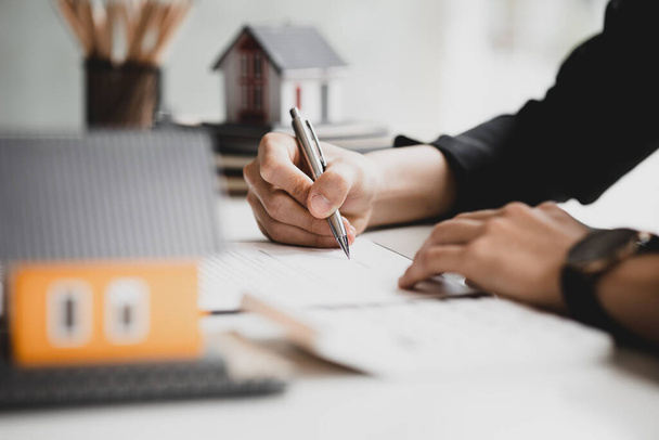 Real estate salespeople are reviewing the real estate sales contract documents before the customer agrees to sign the contract to buy the housing in the project. Real estate trading concept. - Photo, image