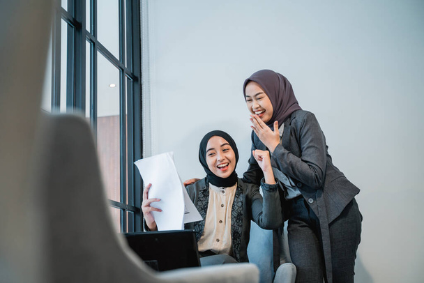 feliz musulmana mujer de negocios levantar el brazo mientras mira el informe de negocios - Foto, Imagen