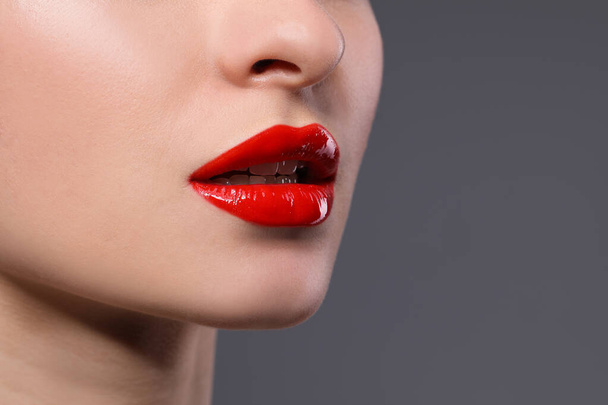 Young woman with beautiful red lips on grey background, closeup. Space for text - 写真・画像