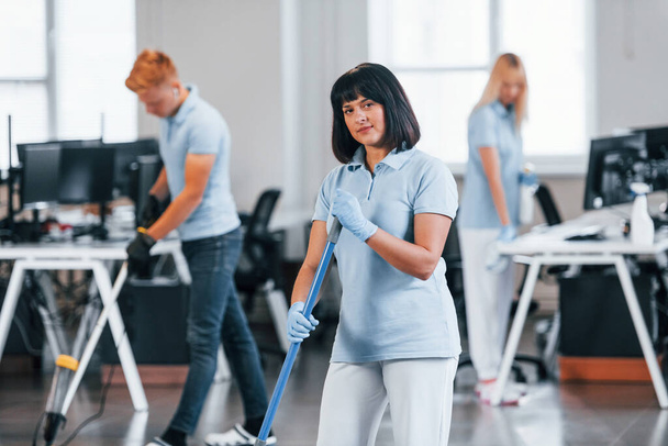 Group of workers clean modern office together at daytime. - Zdjęcie, obraz