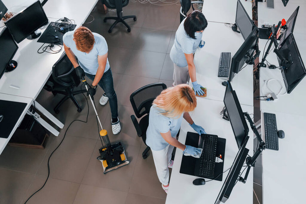 Top view. Group of workers clean modern office together at daytime. - Photo, image