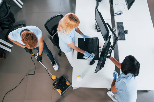 Top view. Group of workers clean modern office together at daytime. - Foto, imagen