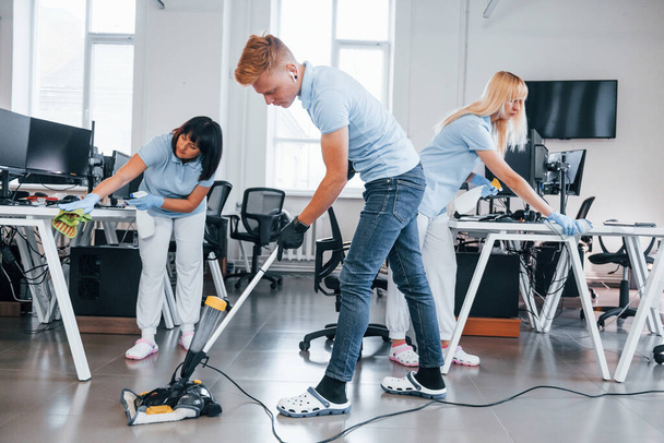 Concentrated at job. Group of workers clean modern office together at daytime. - Zdjęcie, obraz