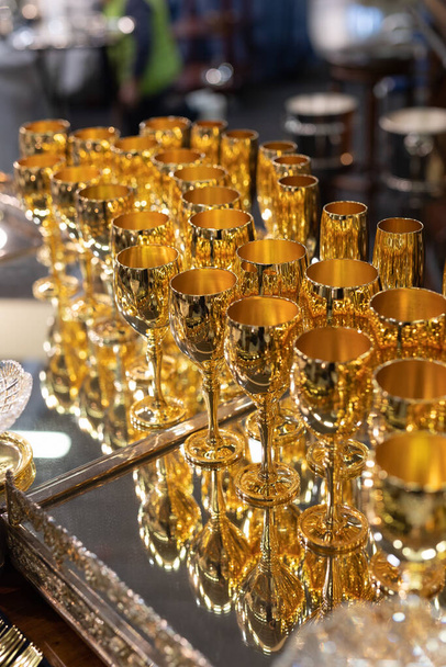 Grupo de cálices dourados dispostos ordenadamente em uma bandeja espelhada com reflexão. - Foto, Imagem
