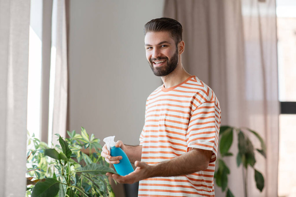 man spraying houseplant with water at home - Foto, Imagen