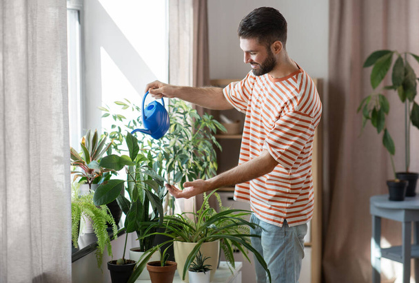 happy smiling man watering flowers at home - Foto, immagini