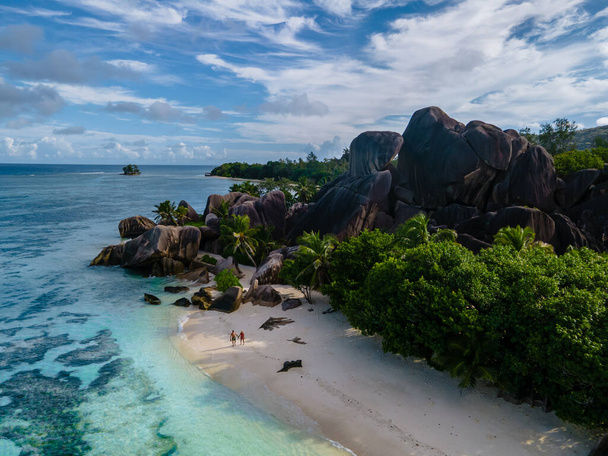 Anse Source dArgent beach, La Digue Island, Seyshelles, Drone aerial view of La Digue Seychelles bird eye view, couple men and woman walking at the beach during sunset at a luxury vacation - Fotó, kép