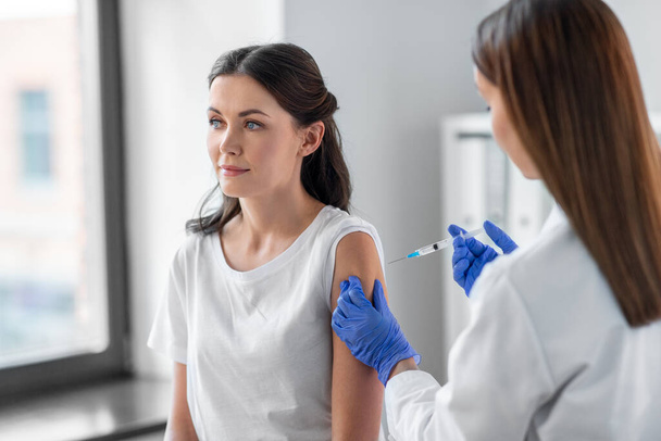 注射器で患者をワクチン接種する女性医師 - 写真・画像