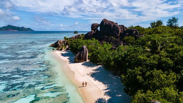 Anse Source dArgent beach, La Digue Island, Seyshelles, Drone légi kilátás a La Digue Seychelles madártávlatból, pár férfi és nő sétál a strandon napnyugtakor egy luxus nyaralás - Fotó, kép