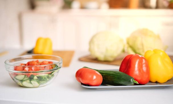 posílení imunity během pandemie koronaviru. Čerstvá zelenina na stole na pozadí bílé kuchyně. Kapusta zelí, rajčata, okurky, paprika, zelí. Beriberi. - Fotografie, Obrázek