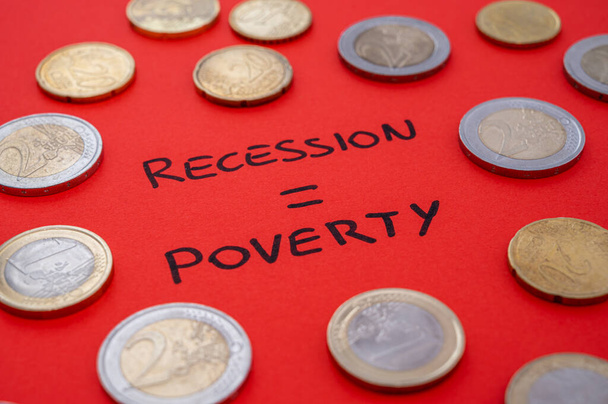 Text "recession poverty" written on red surface and few coins around. Poverty and economic difficulties due to recession and economic crisis. - Fotó, kép