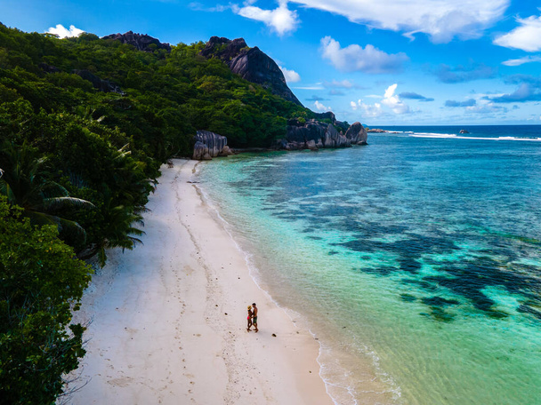 Anse Source dArgent beach, La Digue Island, Seyshelles, Drone légi kilátás a La Digue Seychelles madártávlatból, pár férfi és nő sétál a strandon napnyugtakor egy luxus nyaralás - Fotó, kép
