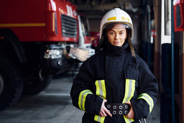 Female firefighter in protective uniform standing near truck. - Zdjęcie, obraz