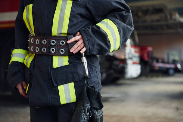 Close up view. Female firefighter in protective uniform standing near truck. - Foto, afbeelding