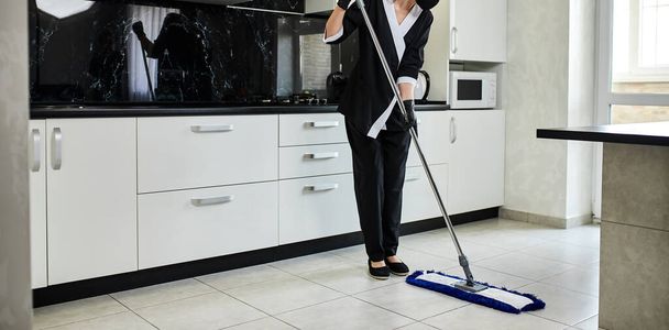 Empresa profesional de servicios de limpieza empleada en guantes de goma con fregona elimina la suciedad del suelo de la cocina, desinfecta y esteriliza - Foto, Imagen