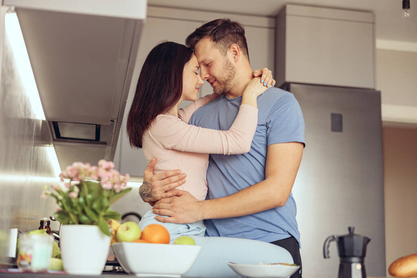 Portrait of couple in love embracing at home interior. man and woman hugging in kitchen. - Fotó, kép