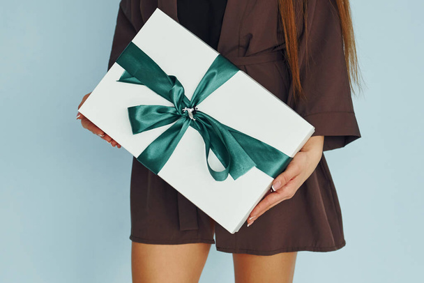 Close up view of young woman that standing against wall with gift box in hands. - Фото, зображення
