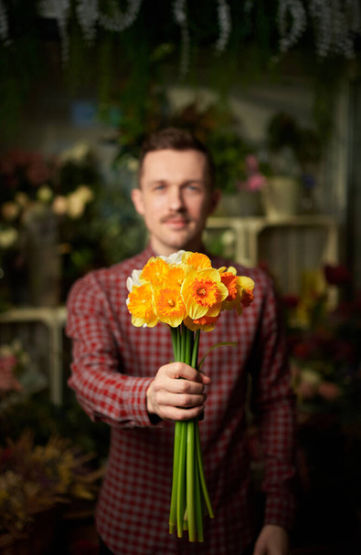 Congratulating concept: man with yellow and orange flower bouquet - Foto, afbeelding