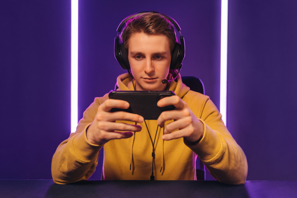 Jogador profissional jogando no jogo de vídeo móvel on-line na sala de néon - Foto, Imagem