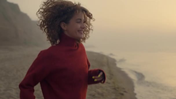 Excited girl jumping on beach. Smiling woman turning around on sea coast - Séquence, vidéo