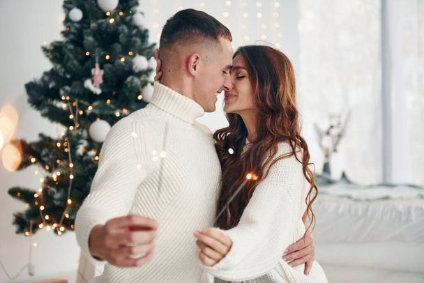 With sparklers in hands. Young romantic couple celebrates New year together indoors. - Foto, Bild