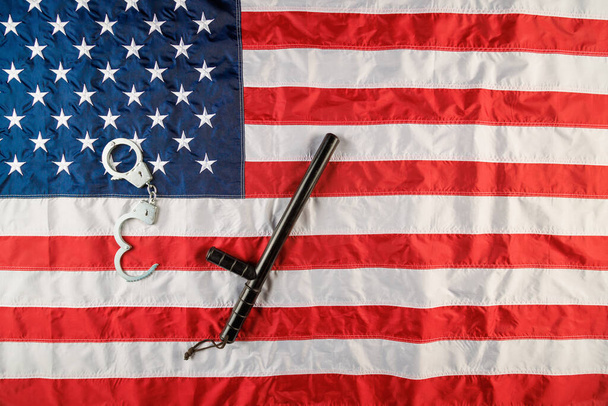 silver metal handcuffs and police nightstick over US flag on flat surface - Foto, Imagem