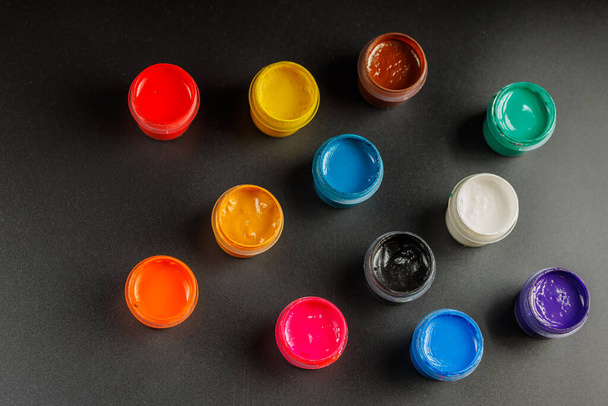 close-up background of opened small gouache paint jars on black surface - Photo, Image