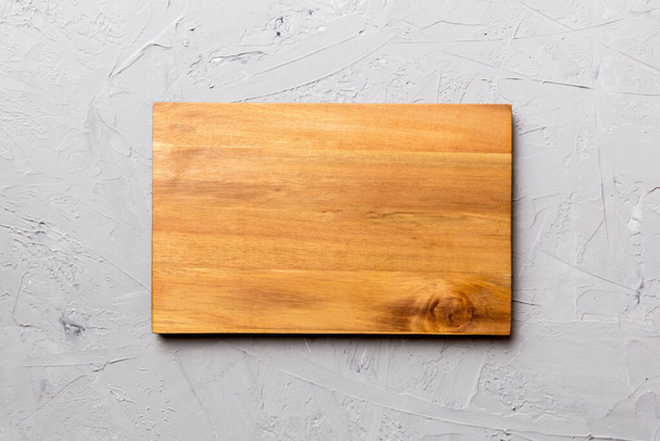 Vista superior de tabla de cortar de madera sobre fondo de cemento. Espacio vacío para su diseño. - Foto, imagen