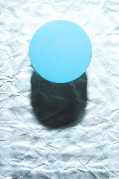 Okrągły niebieski obiekt na abstrakcyjnym niebieskim tle. Minimalistyczny płaski leżał pojedynczy obiekt z cieniem. - Zdjęcie, obraz