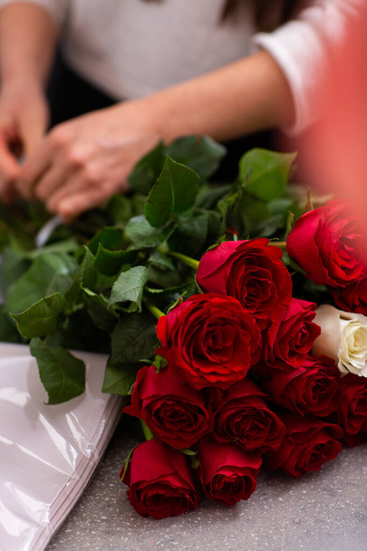 Florist at work. Close-up female hands cut roses Woman making a bouquet of red roses for valentines day. Fresh roses for bouquet delivery - Φωτογραφία, εικόνα
