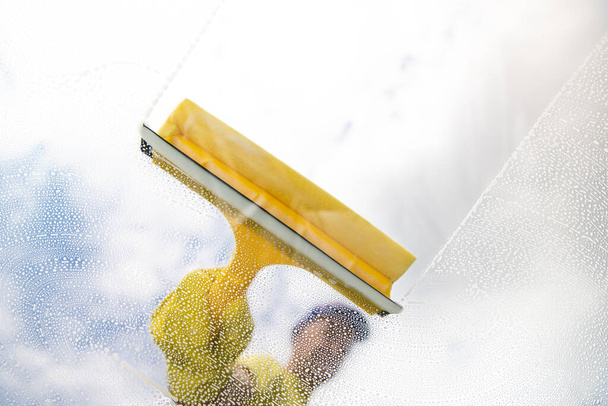 window cleaner cleaning window with squeegee and wipe - Photo, Image